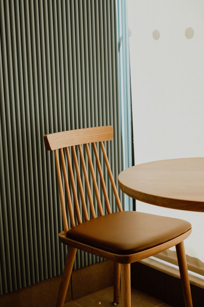 Stylish wooden dining chair and table set in sunlit room with modern decor.