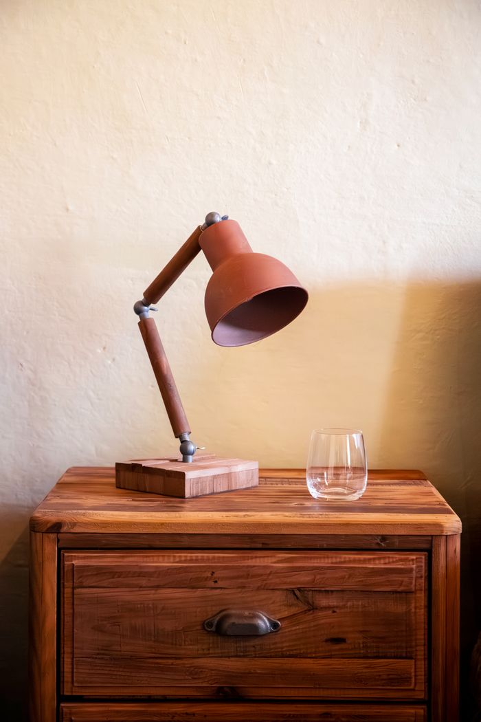 A rustic wooden table featuring an industrial lamp and an empty glass, casting a warm ambiance.