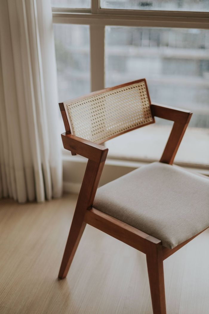 Stylish mid-century modern wooden chair with fabric seat in a bright sunlit room.