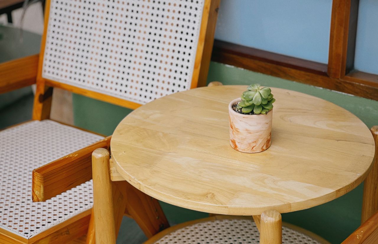 about-02 Wooden table and chair with a succulent plant create a cozy indoor setting in Vietnam.