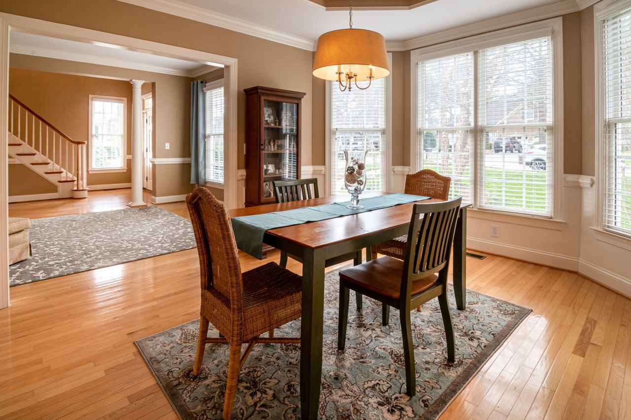 about-img A sunlit dining room featuring a wooden table and wicker chairs, showcasing luxury interior design.